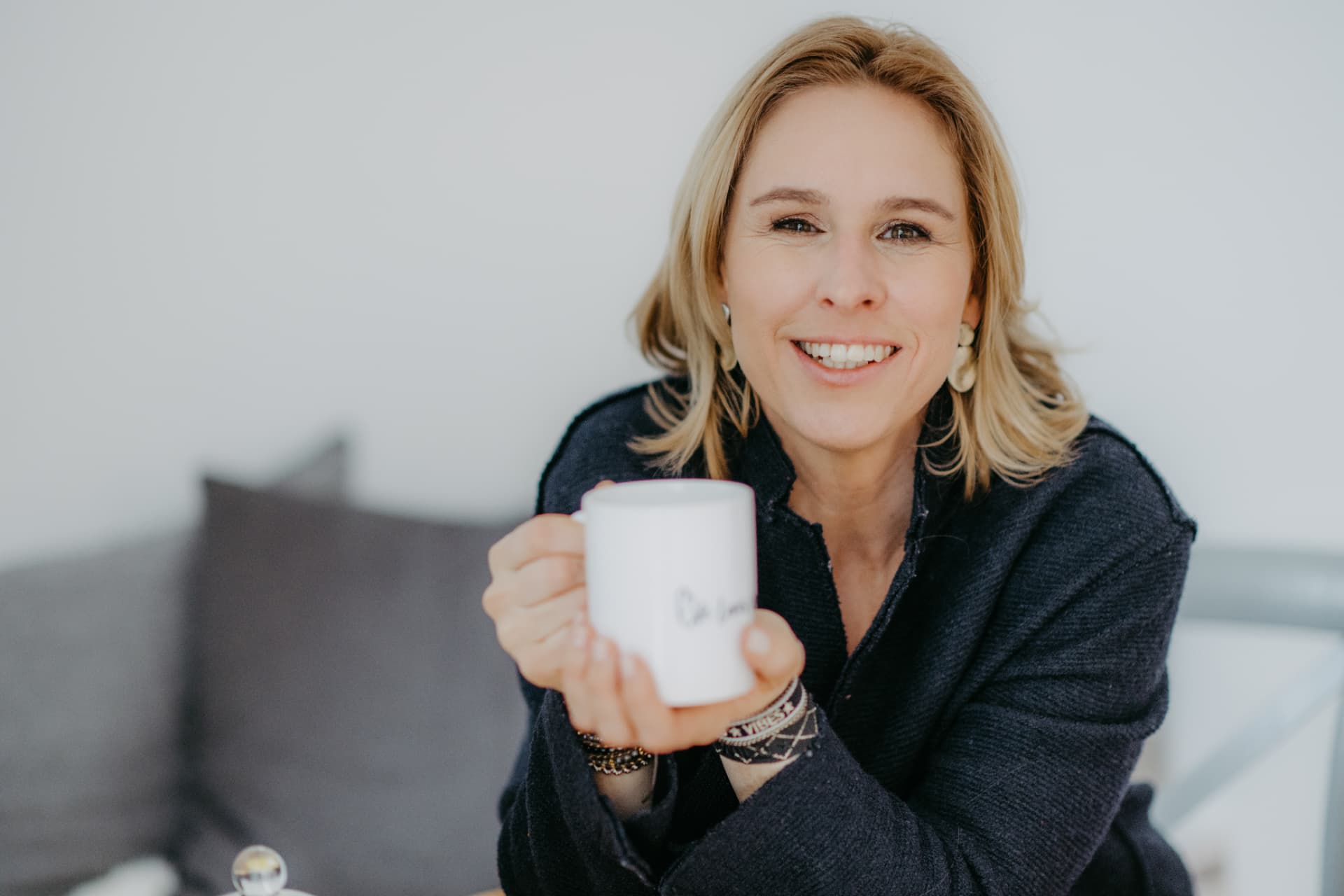 Raffaela Lobner lächelt in die Kamera und hält eine Tasse in den Händen